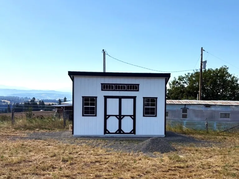 White Cascade Series shed with black trim, double doors, and transom windows overlooking the valley