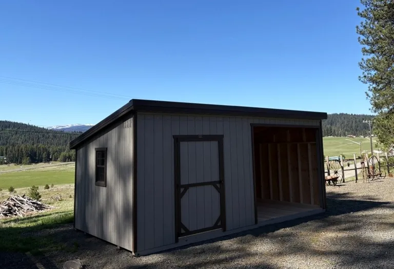 Tan Cascade Series shed with dark trim and open bay in a mountain meadow