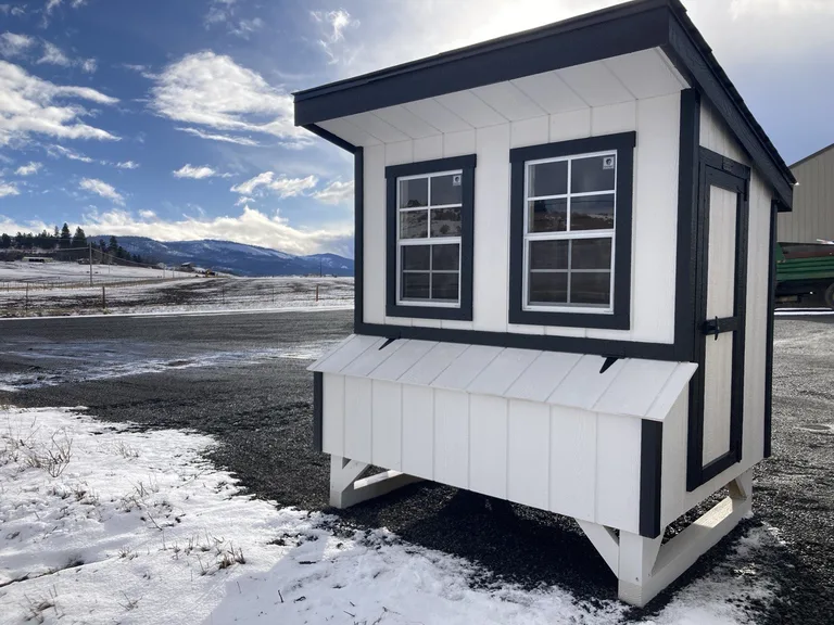 White chicken coop with black trim and two windows on a display lot