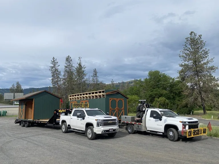Delivery crew maneuvering a storage shed into place