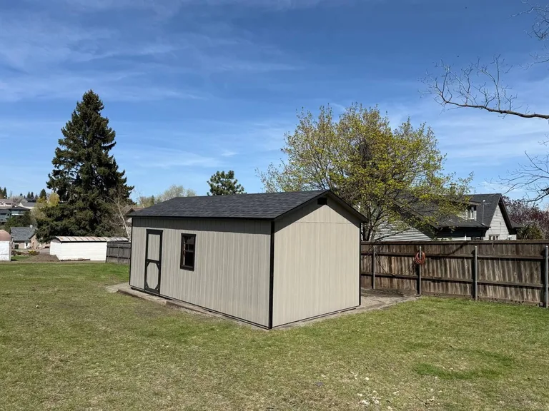 Tan garage with dark roof in a fenced backyard