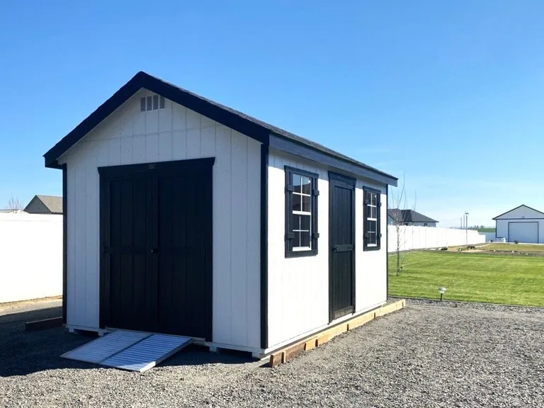 White garage with black double doors and window shutters on a display pad