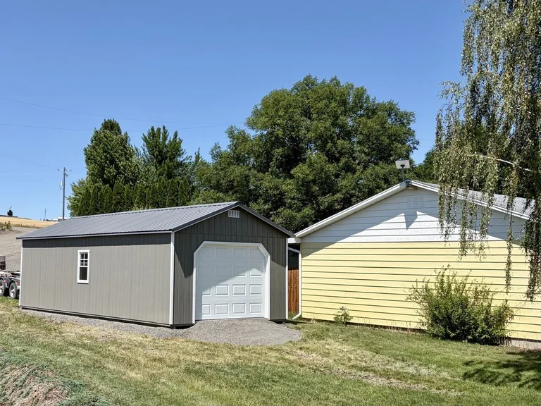 Gray garage with white overhead door installed beside a home