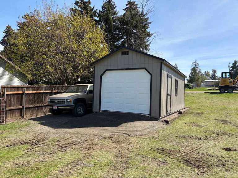 Brown garage with white overhead door parked next to a classic pickup truck