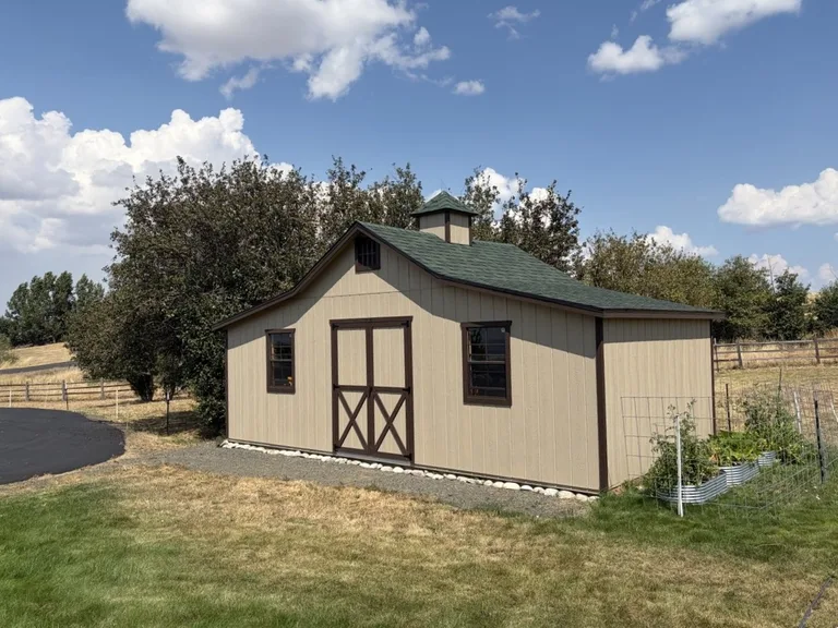 Tan rancher barn with a green roof, cupola, and front windows