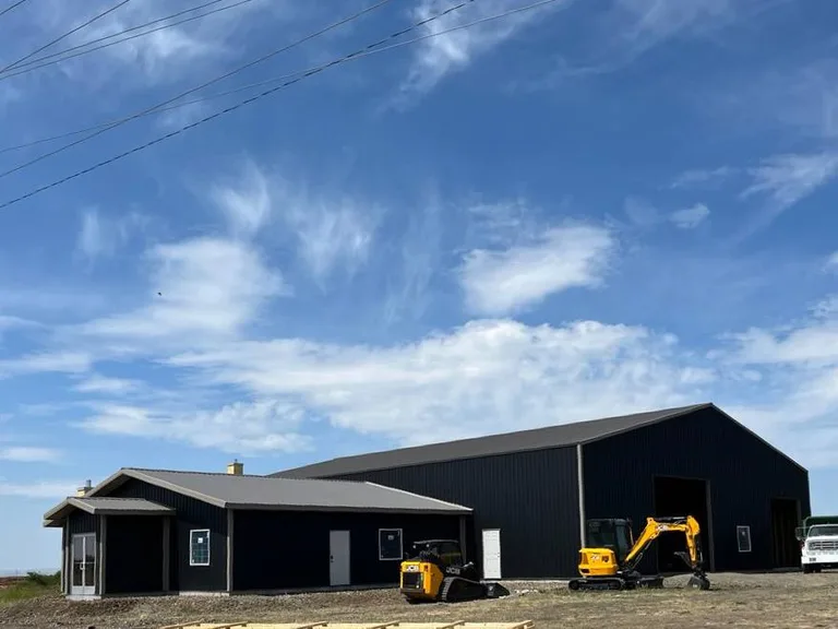 Large black metal-sided shop buildings with equipment out front